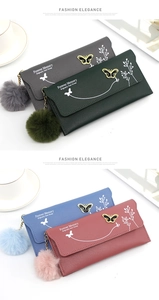 Close-up of long women's wallets with butterfly floral prints and pompom charms