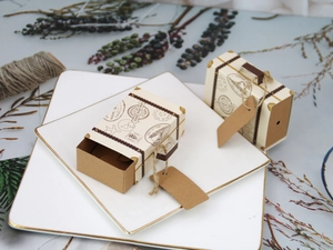 Mini suitcase paper candy boxes with retro postmark design on white porcelain plate