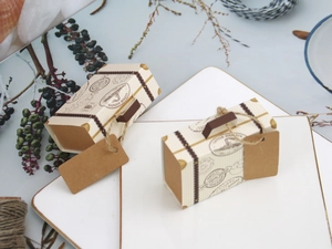 Detailed view of mini travel suitcase favor boxes with vintage prints on white trays