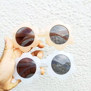 Detail of flower-shaped children's sunglasses in apricot and white plastic frames