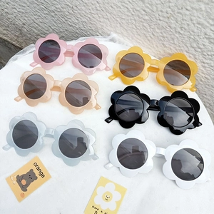 Flat lay of flower-shaped kids sunglasses in pink, yellow, blue, and white colors