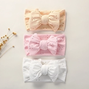 Three soft nylon baby headbands in peach, pink and white with hollow bow detail
