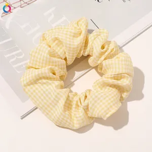 Detailed view of yellow and white gingham fabric scrunchie on a minimalist desktop