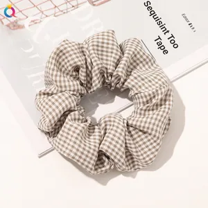 Detail of a brown plaid scrunchie with soft fabric texture on a lifestyle background