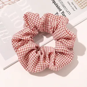 Detailed close-up of a red and white gingham fabric scrunchie on a vintage magazine page