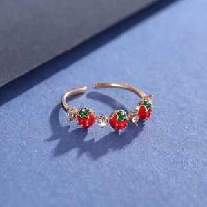 Detail of gold strawberry ring with red enamel and sparkling crystal accents