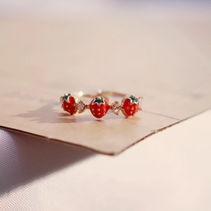 Macro shot of gold strawberry ring with sparkling crystals and green leaf details