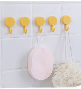 Row of five yellow rotating bathroom hooks mounted on white tiles with shower sponges