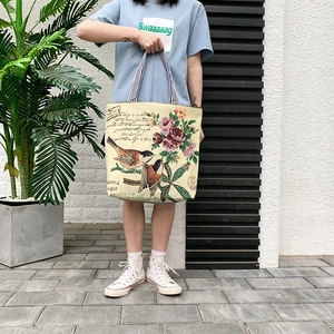 Detail of vintage beige canvas tote bag featuring floral bird patterns and fabric texture