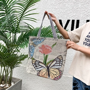 Close-up of ethnic canvas tote bag featuring jacquard butterfly print and striped handles