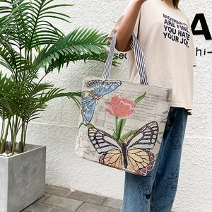 Detail of canvas tote bag featuring vibrant butterfly and tulip prints with striped straps