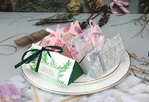Vista dettagliata di scatole regalo triangolari assortite con eleganti nastri su un piatto