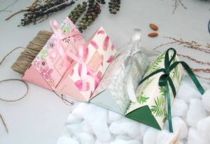 Dettaglio di scatole regalo triangolari con motivi floreali, marmo e nastri eleganti