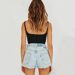 Detailansicht eines sexy rückenfreien schwarzen Falten-Tops mit ausgefransten Jeansshorts