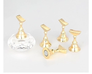 Macro view of magnetic golden nail tips stands on a diamond-shaped acrylic crystal base