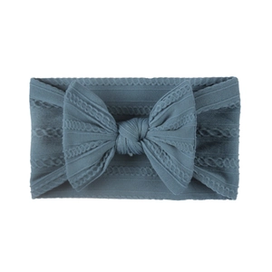 Detail of soft greyish blue knitted baby headband with a jacquard bow for newborns