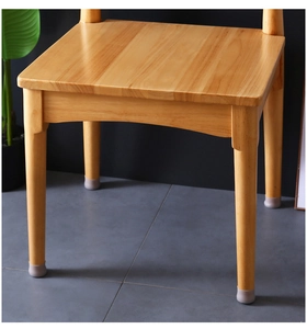 Close-up of grey silicone floor protectors on light wood chair legs for surface protection