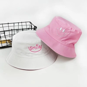 Close-up of white and pink cotton bucket hats with high-quality smile embroidery detail
