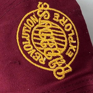Gros plan sur la broderie jaune d'une casquette de baseball en sergé de coton rouge foncé