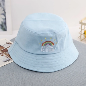 Close-up of rainbow embroidery and Radiate Positivity text on a light blue sun hat