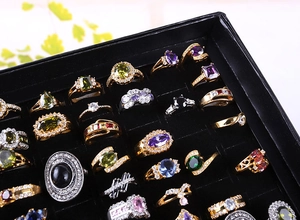 Close-up of luxury 100-slot jewelry display box filled with colorful gemstone rings