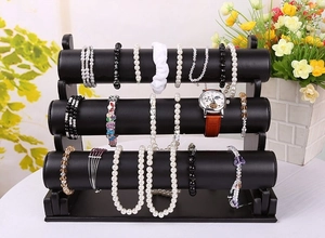 Three-tier black jewelry display stand for necklaces and bracelets in a macro view