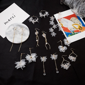 Elegant white petal drop earrings and gold daisy studs set on a sleek black backdrop