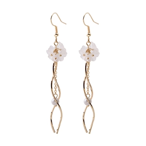 Detail of floral drop earrings featuring white petals, gold metal swirls, and small pearls