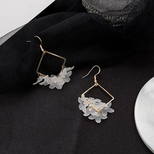 Close-up of gold geometric square earrings with frosted translucent white petal drops