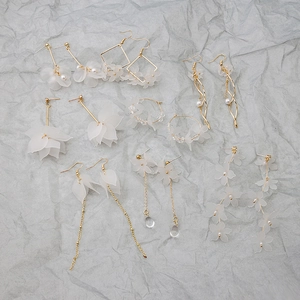 Detail of white translucent flower earrings with gold alloy and faux pearl accents