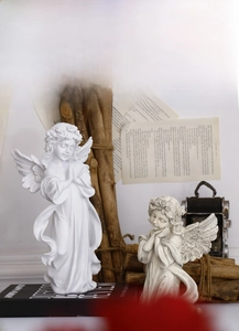 Close-up of white and grey resin angel statues showing detailed wings and praying pose