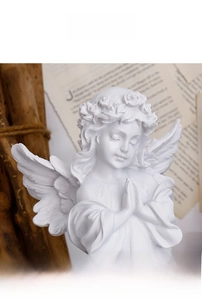 Close-up of white resin praying angel sculpture with flower crown and detailed wings