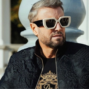 Close-up of white chunky frame sunglasses with black temples on model in natural light