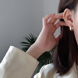 Close-up of gold irregular textured S925 silver stud earrings worn by a model