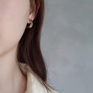 Close-up of gold irregular hammered hoop earring worn on model's ear for size detail