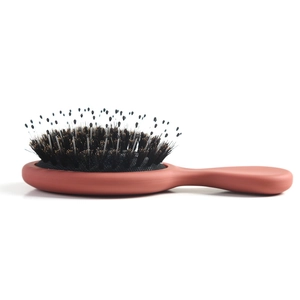 Detail of ergonomic brick red handle and mixed boar bristles on air cushion brush