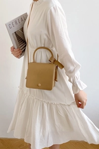 Close-up of beige minimalist PU leather square handbag with top handle and shoulder strap
