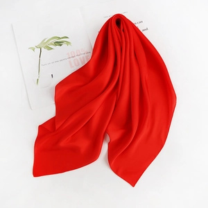 Close-up of a smooth red silk square scarf draped over an open fashion magazine