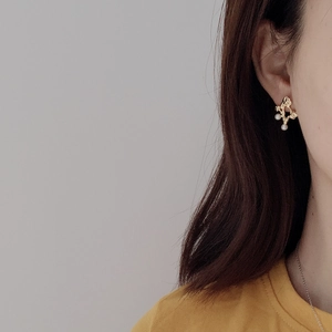 Detailed close-up of golden irregular openwork pearl stud earrings on a female model