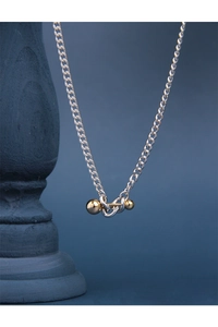 Detail of silver chain with dual gold spheres pendant on a classic blue column