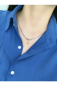 Detail of S925 sterling silver bar and ball necklace worn over a blue shirt