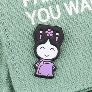 Cartoon girl in traditional Chinese attire enamel brooch on green textured fabric