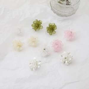 Close-up of translucent pastel flower earrings on a textured paper background