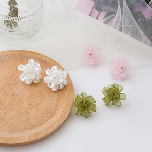 Macro detail of matte resin flower earrings in white, pink, and green pastel tones
