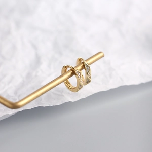 Macro shot of gold faceted hoop earrings with inlaid micro-diamonds on a metal display