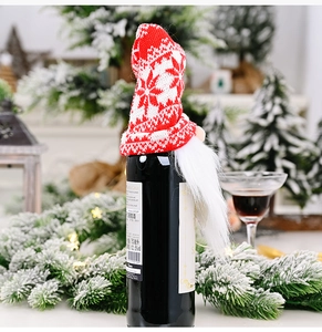Close-up of Christmas gnome wine bottle cover with red snowflake knitted hat and white beard
