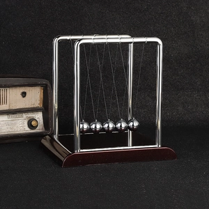 Pendolo di Newton con cinque sfere di metallo e base in legno marrone rossiccio scuro