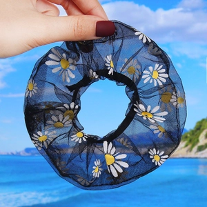 Detail of black daisy print organza scrunchie with elastic hair tie on beach background