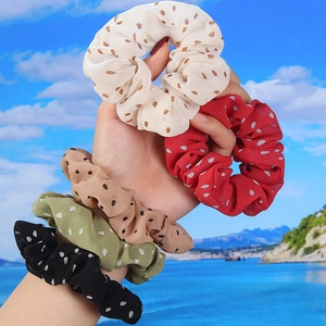 Close-up of colorful polka dot chiffon scrunchies in five retro summer shades on a wrist