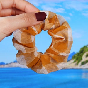 Detail of orange and white gingham scrunchie with semi-transparent organza fabric